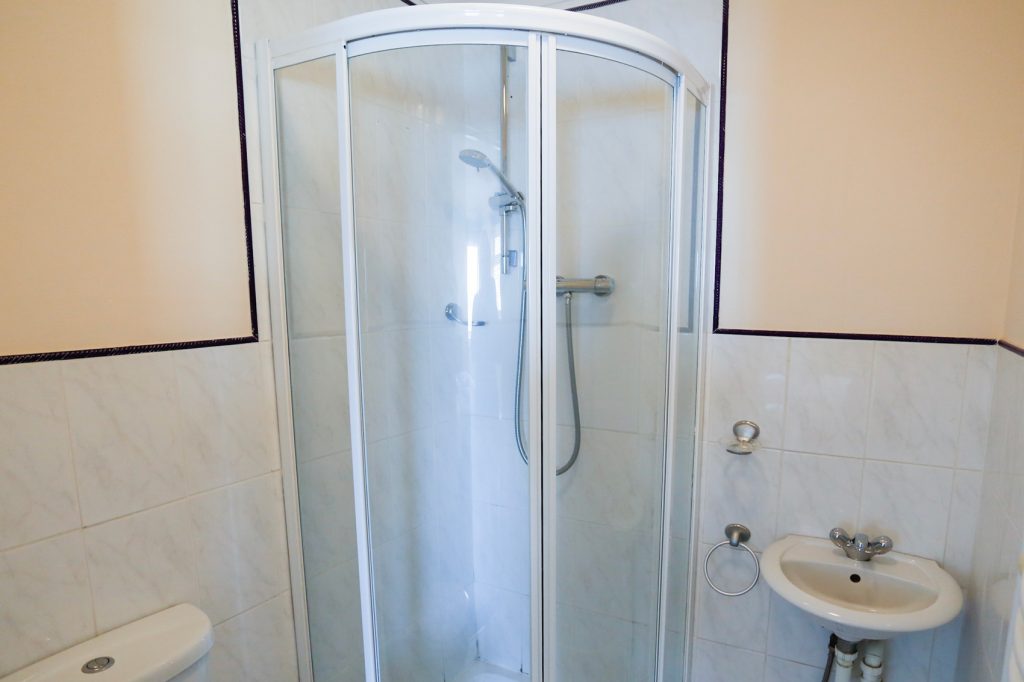 Bathroom with enclosed shower, wash basin right, toilet right