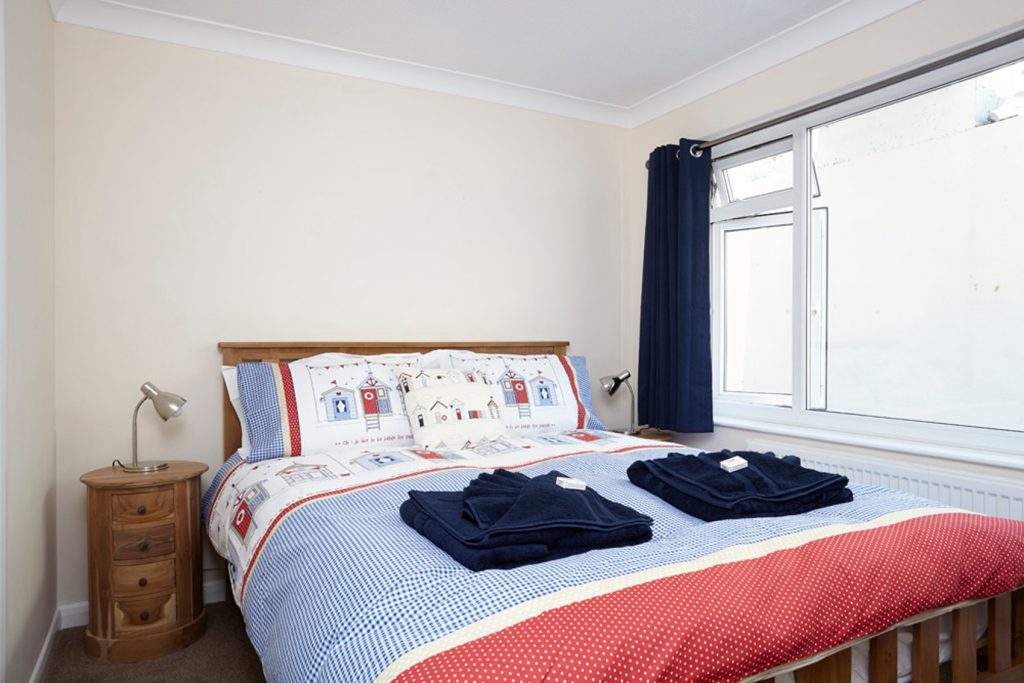Bedroom 2, double bed with 2 bedside tables. Towels neatly folded on top of bed ready for guests